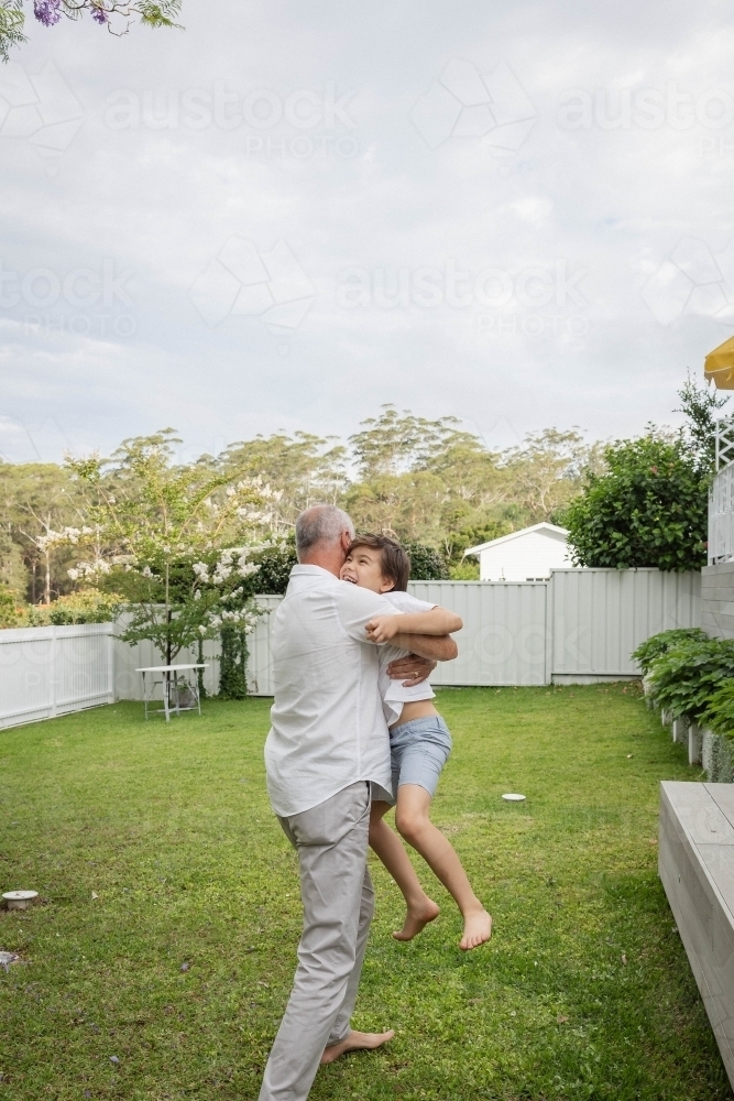 Grandad and grandson hugging in backyard - Australian Stock Image