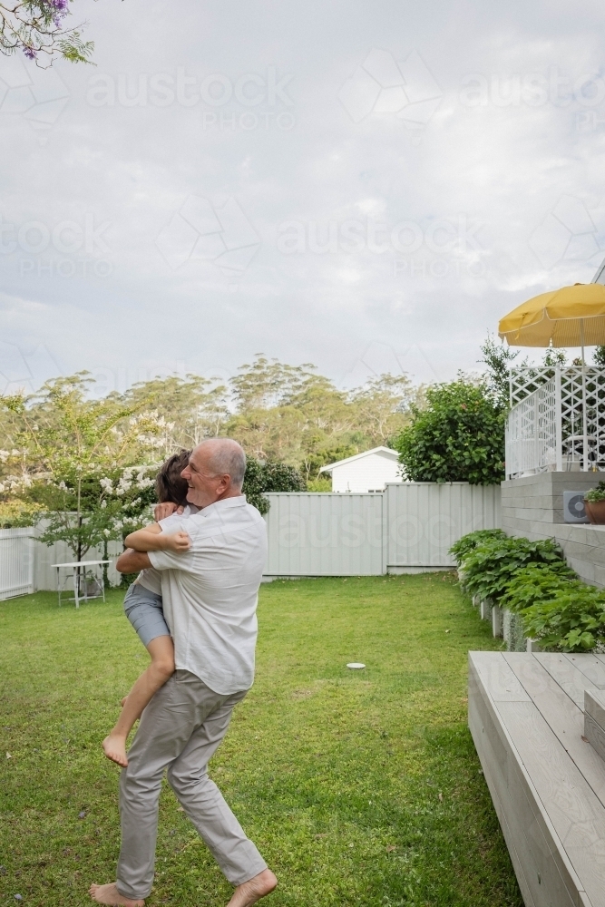Grandad and grandson hugging in backyard - Australian Stock Image