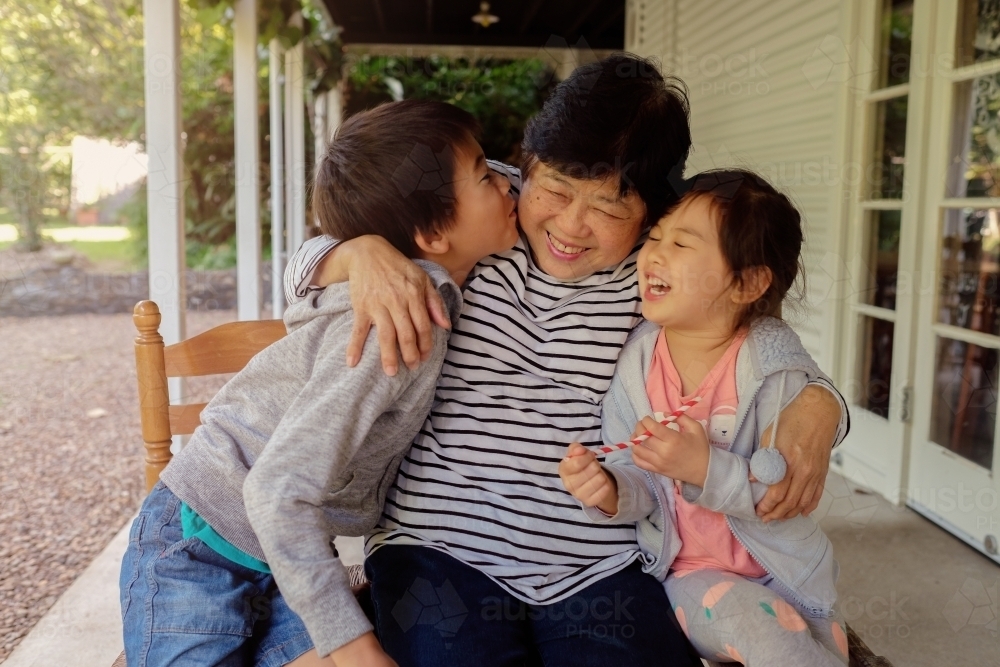 Grandchildren kissing their grandmother - Australian Stock Image