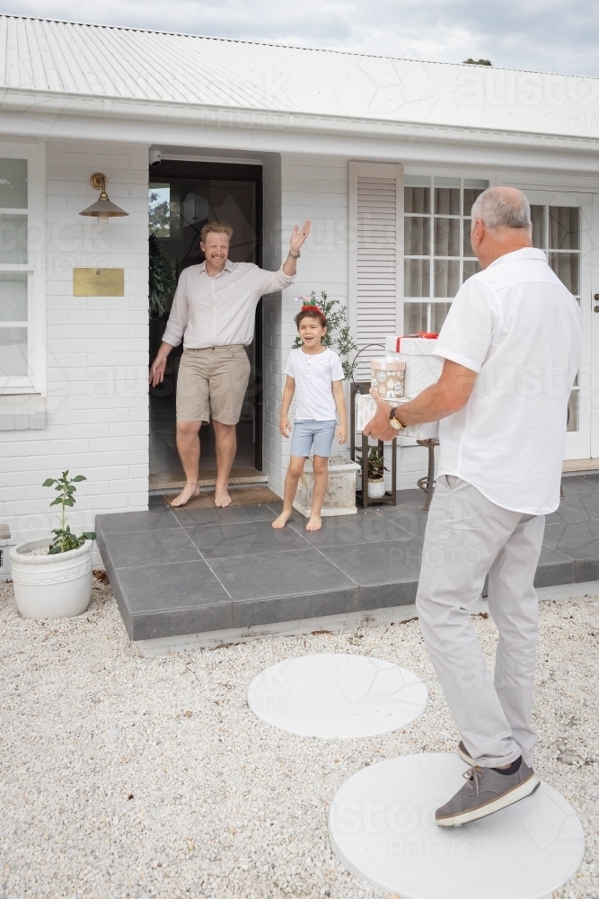 Grandfather bringing Christmas presents for father and son at home - Australian Stock Image