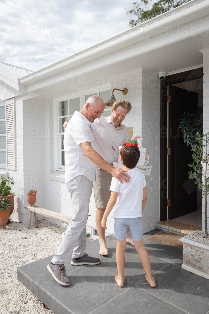 Grandfather, father and son at front door of home with Christmas presents - Australian Stock Image