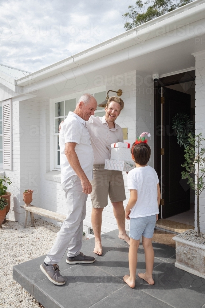 Grandfather, father and son at front door of home with Christmas presents - Australian Stock Image