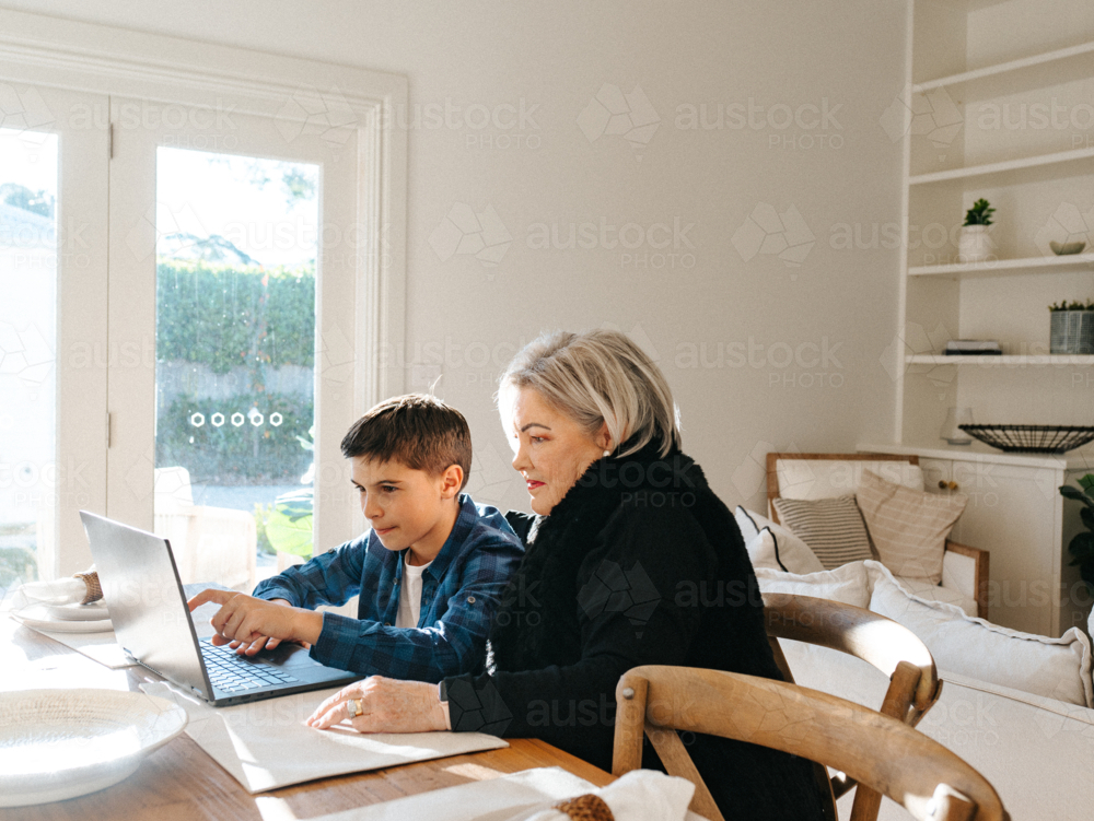 Grandma sitting with her grandson in front of a laptop on the table. - Australian Stock Image