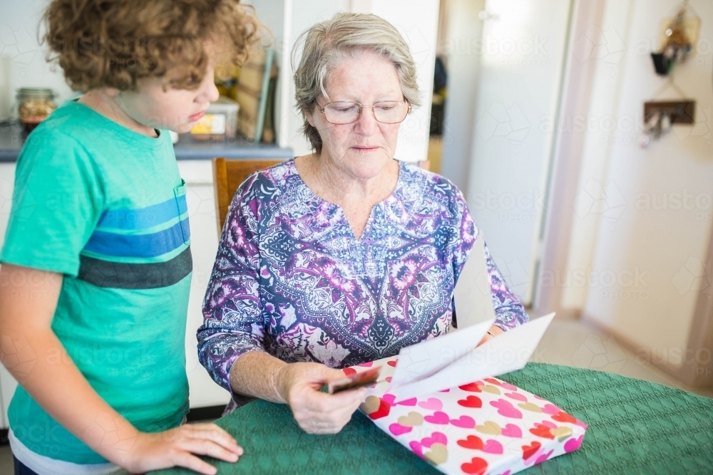 Grandmother opening present reading card with grandchild - Australian Stock Image
