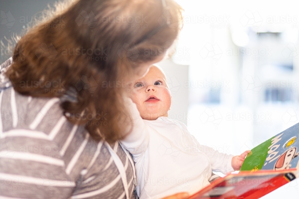 Grandmother reading book with baby grandchild - Australian Stock Image
