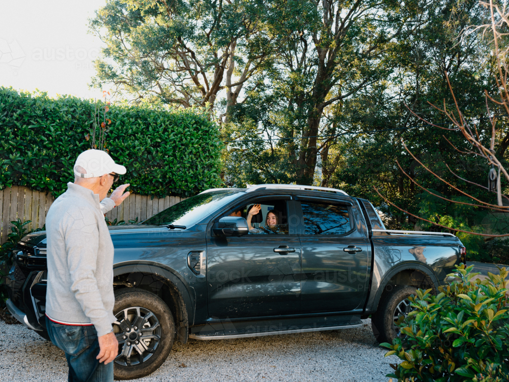 Grandpa waving goodbye to his granddaughter in the car - Australian Stock Image