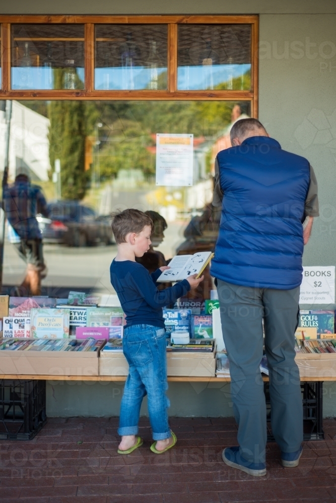 Grandpa with boy reading books outside shop - Australian Stock Image