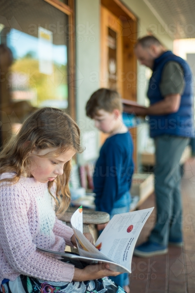 Grandpa with children looking at books at shop - Australian Stock Image