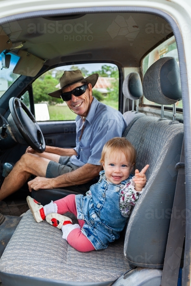 Granduncle farmer with baby grand niece sitting in farm ute smiling - Australian Stock Image