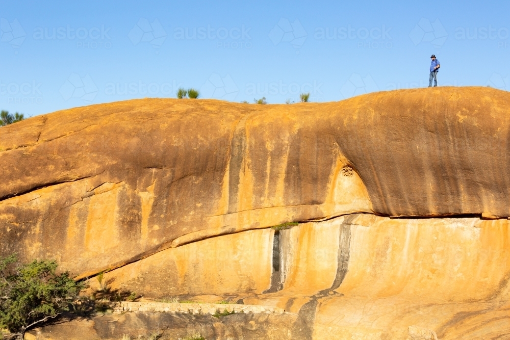 granite rock formation in wheatbelt with human figure on top for scale - Australian Stock Image