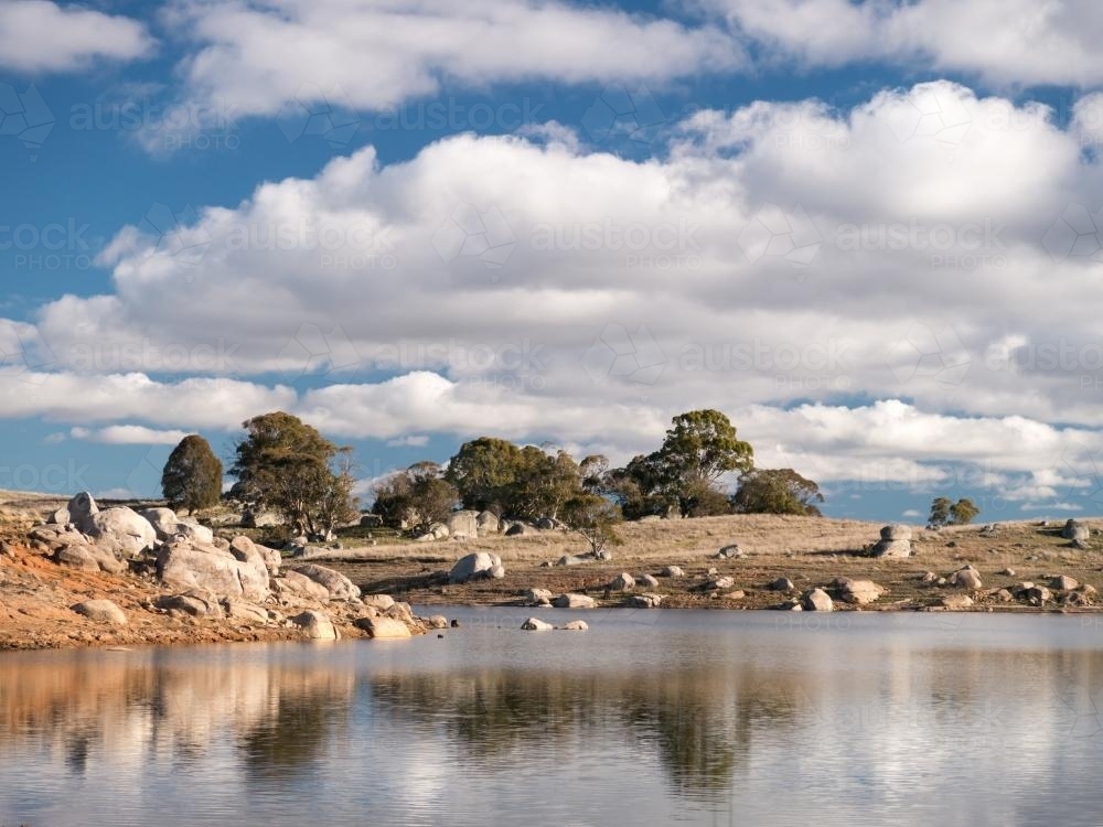 Granite rock lake scene on a sunny day with scattered cloud - Australian Stock Image