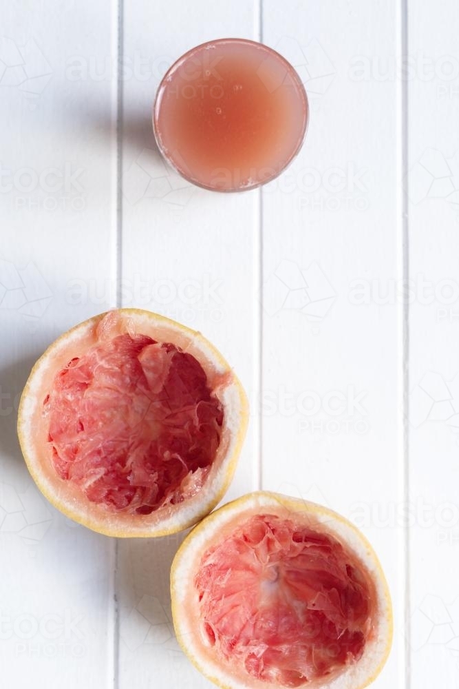 grapefruit juice with squeezed fruit on white background - Australian Stock Image