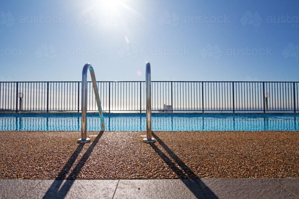 Graphic lines and patterns in swimming pool with sun flare - Australian Stock Image