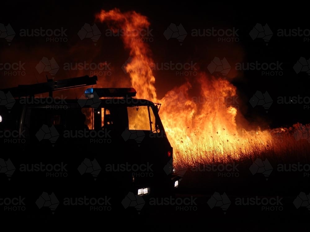 Grassfire at night with silhouette of firetruck - Australian Stock Image