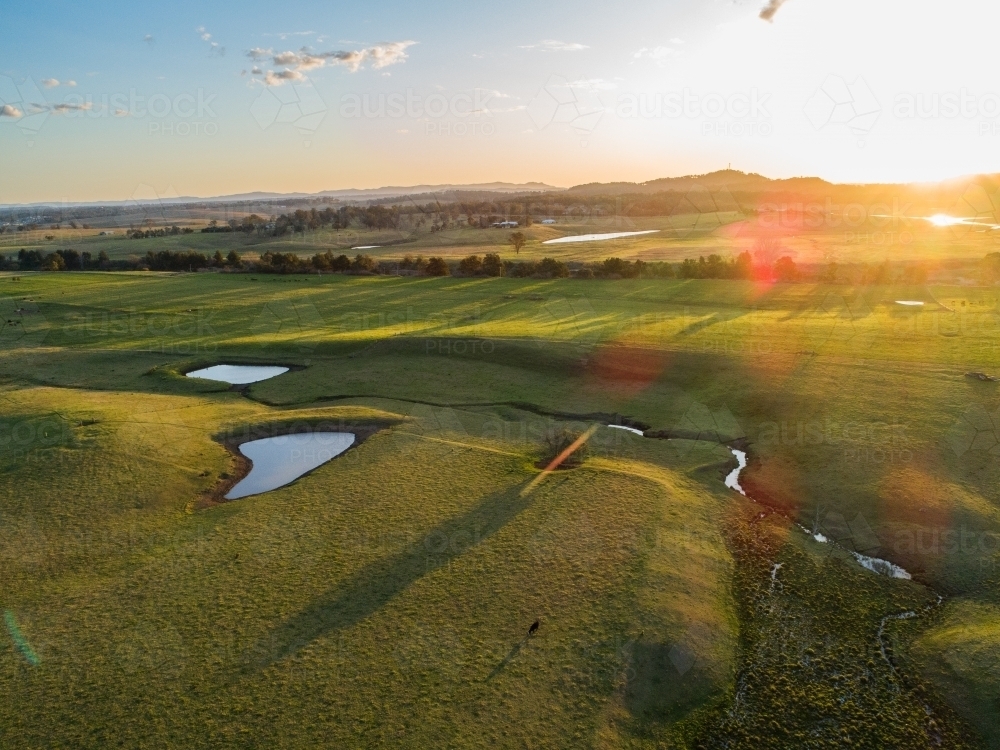 Green Australian farmland landscape with dams and creek at sunset - Australian Stock Image
