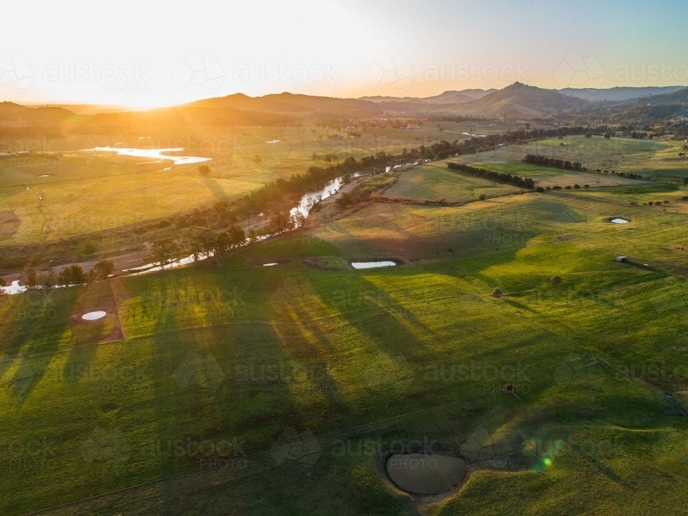 Green Australian farmland with Hunter River flowing through it at sunset  - Australian Stock Image