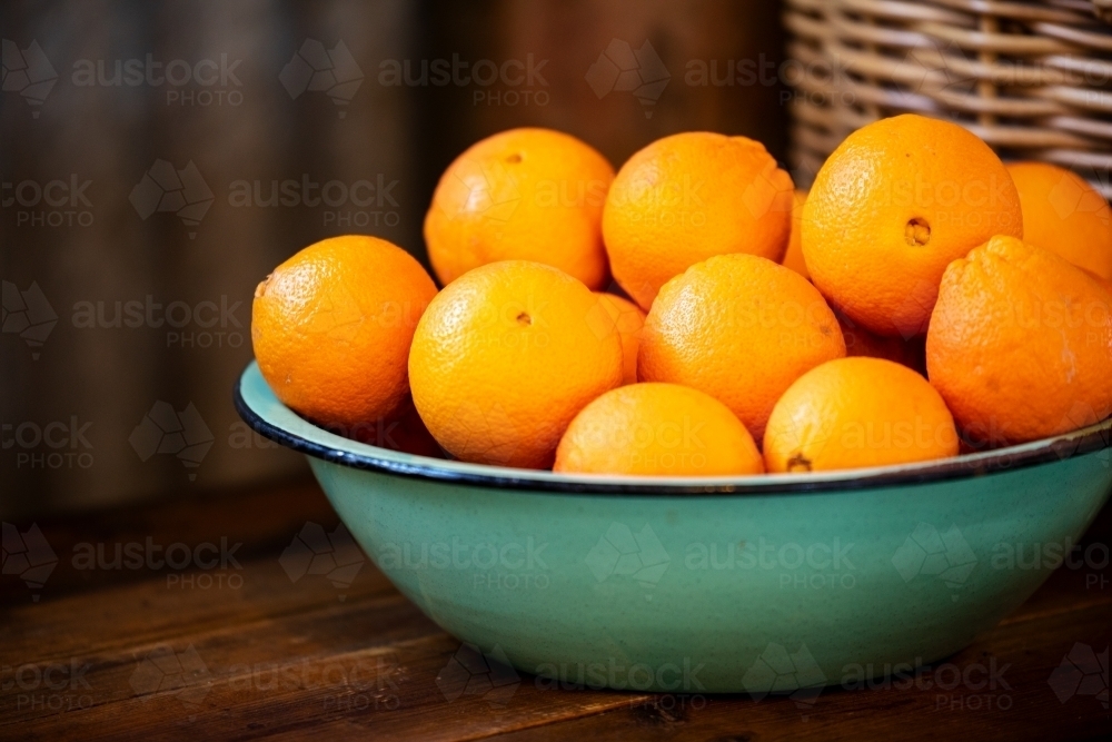 green enamel bowl of oranges - Australian Stock Image
