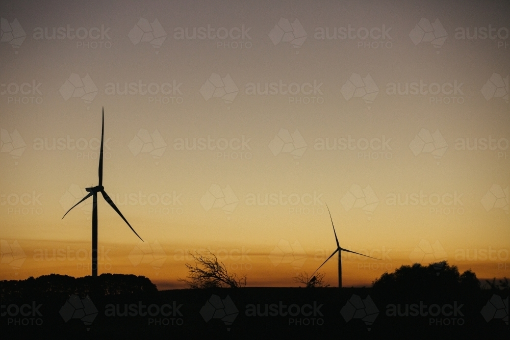 Green energy wind turbine silhouette in the countryside at dusk - Australian Stock Image