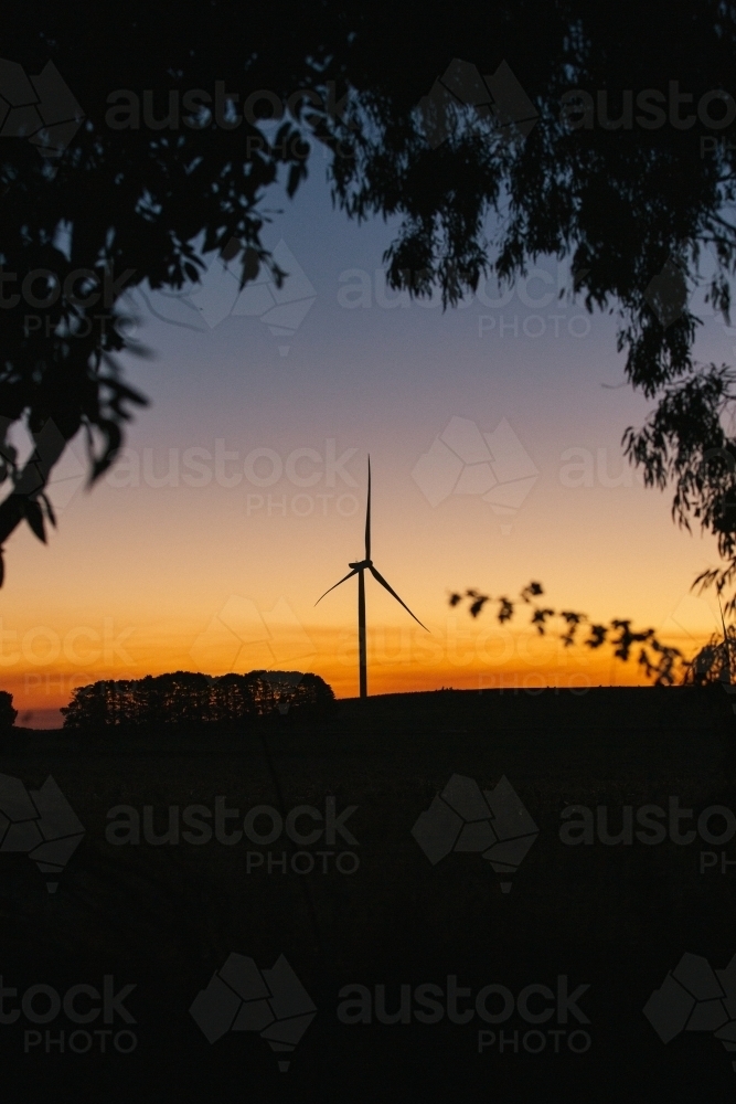 Green energy wind turbine silhouette in the countryside at dusk - Australian Stock Image