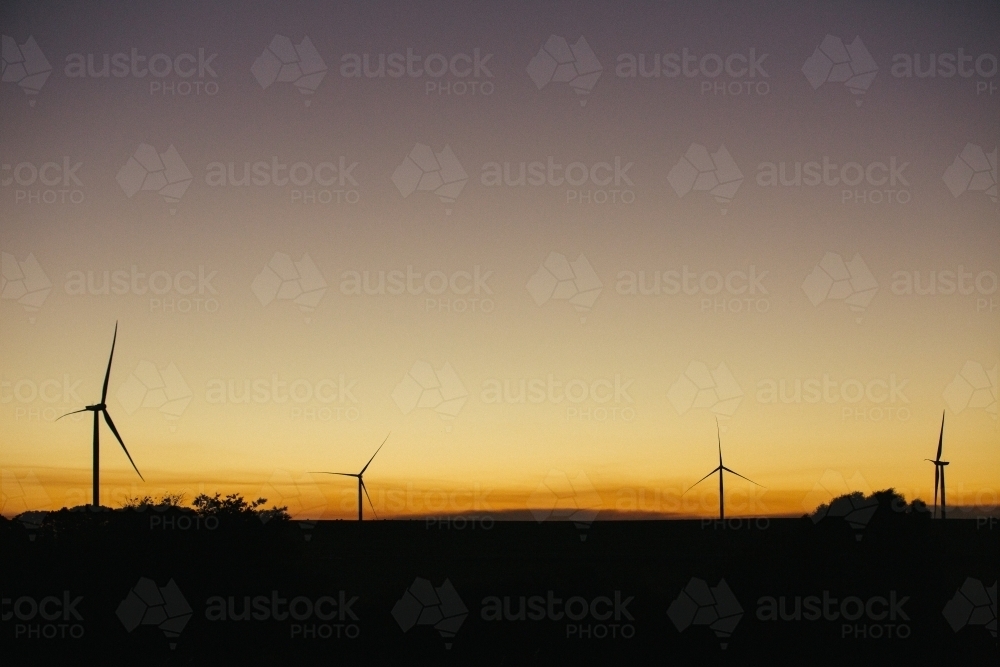 Green energy wind turbine silhouette in the countryside at dusk - Australian Stock Image