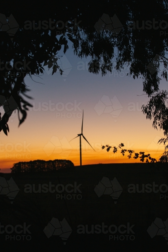Green energy wind turbine silhouette in the countryside at dusk - Australian Stock Image