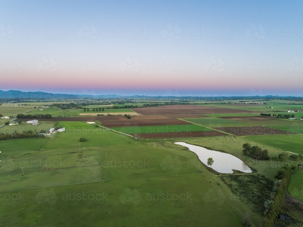 Green farmland landscape at dusk seen from aerial view - Australian Stock Image