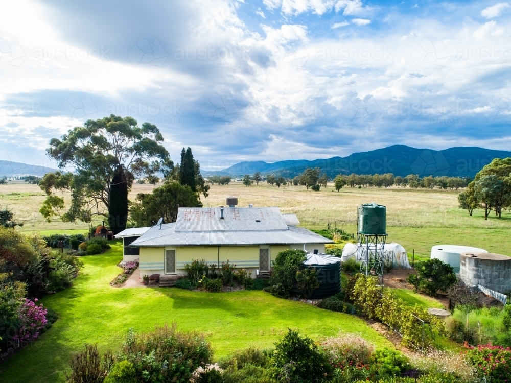 Green front lawn and garden of farm homestead house seen from aerial view on aussie property - Australian Stock Image