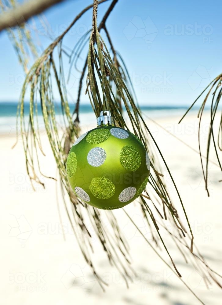 green glitter christmas ornament on a tree at the beach - Australian Stock Image