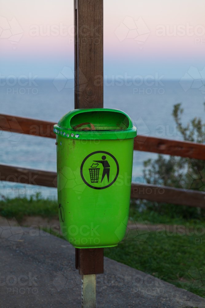 Green rubbish bin mounted on wooden pole in public park - Australian Stock Image
