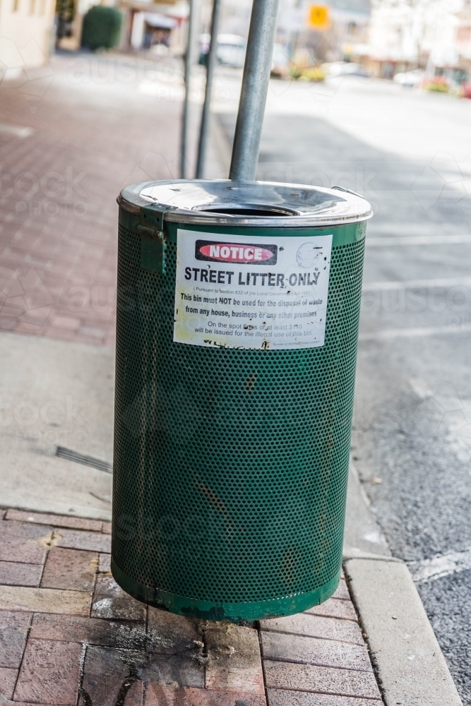 Green rubbish bin on street with litter notice - Australian Stock Image