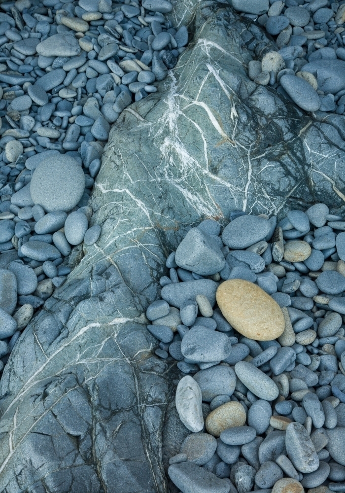 Grey-blue rounded waterworn rocks on the shore - Australian Stock Image