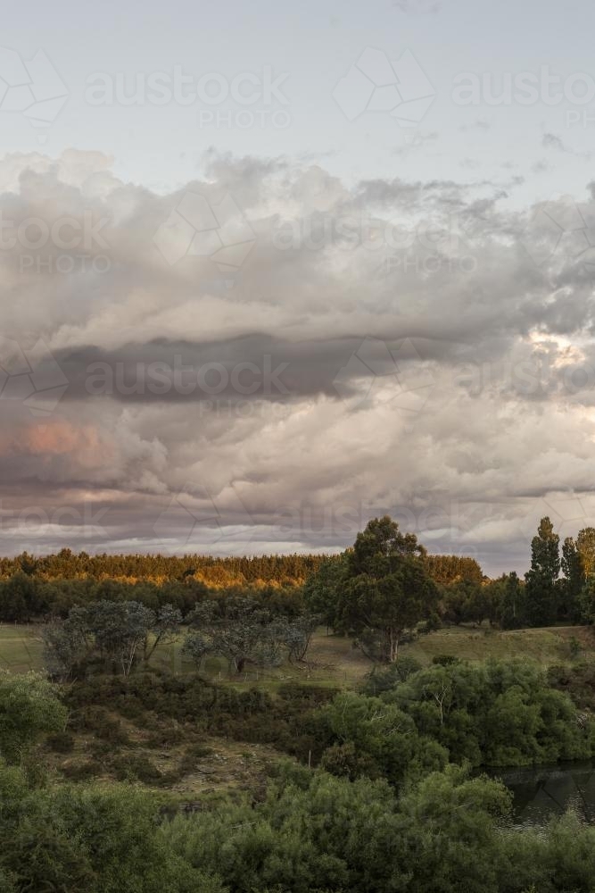 Grey clouds at sunset over river - Australian Stock Image