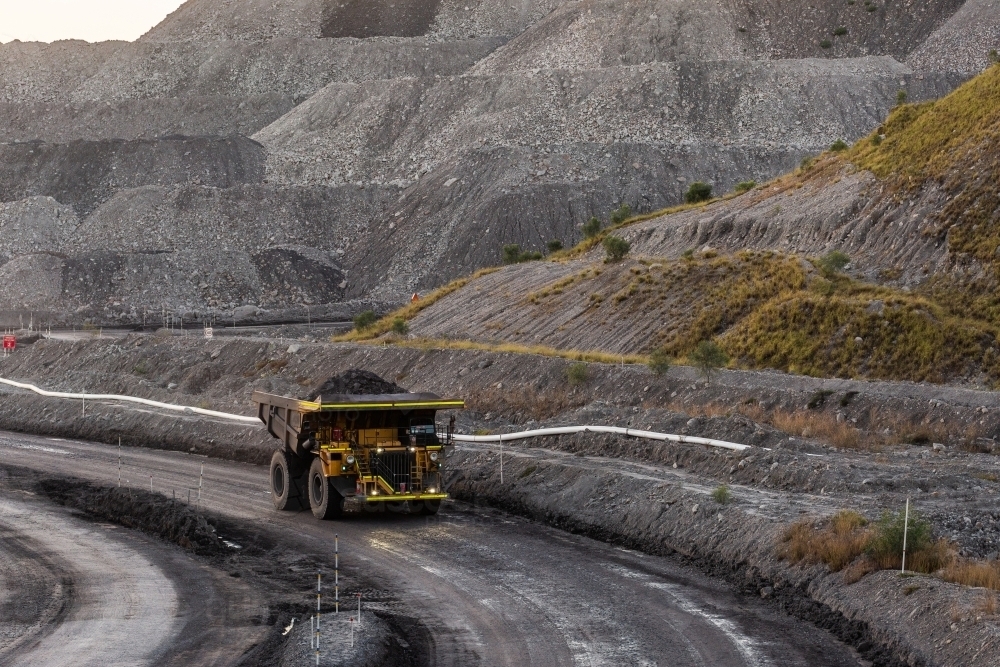 Grey open cut mine hills with dump truck machinery working at earthmoving job - Australian Stock Image