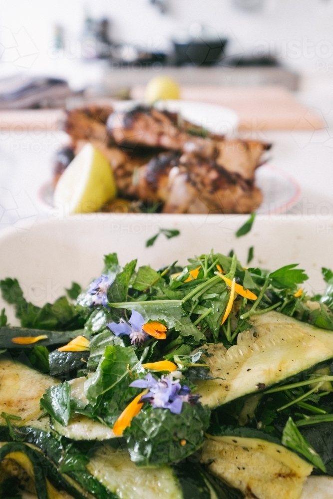 Grilled chicken with lemon and a grilled zucchini salad with edible flowers - Australian Stock Image