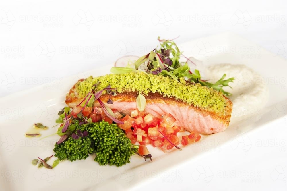 Grilled salmon on a bed of salsa with brocollini and herb crumb - Australian Stock Image