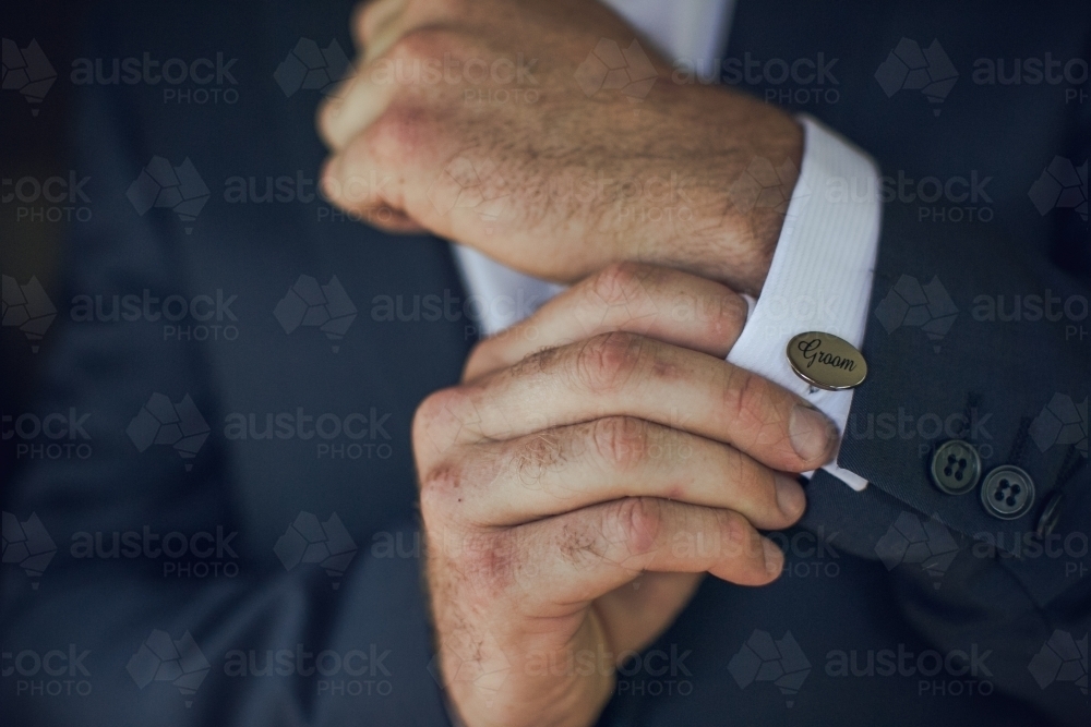 Groom's hands as he does up his cufflinks on his wedding day - Australian Stock Image