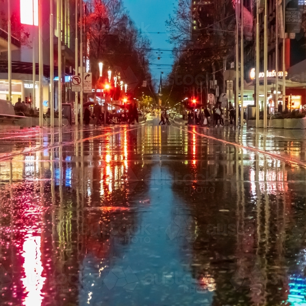Ground level view of a wet city street at night with colourful reflections - Australian Stock Image