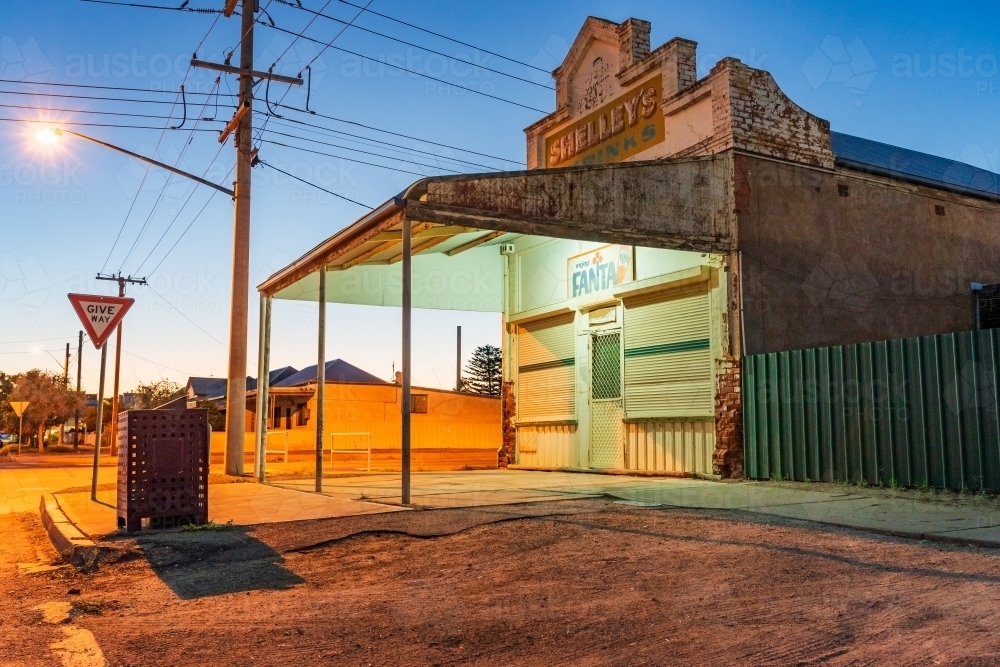 Ground level view of an old fashioned corner store at twilight with streets and power lines - Australian Stock Image