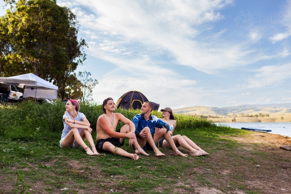 Group of Aussie teens sitting together together on a summer afternoon by a lake - Australian Stock Image