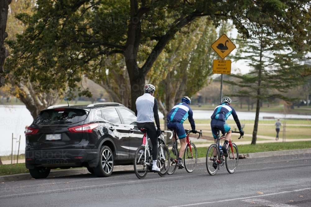 Group of cyclists riding on a bike path around a lake - Australian Stock Image