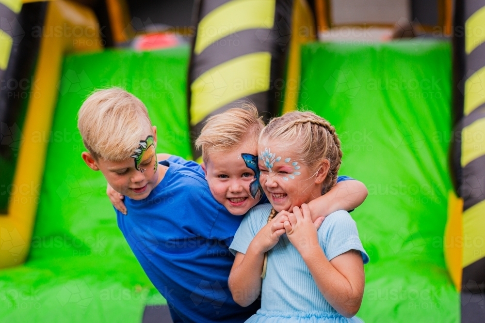 Group of happy kids together at event with jumping castle in background - Australian Stock Image