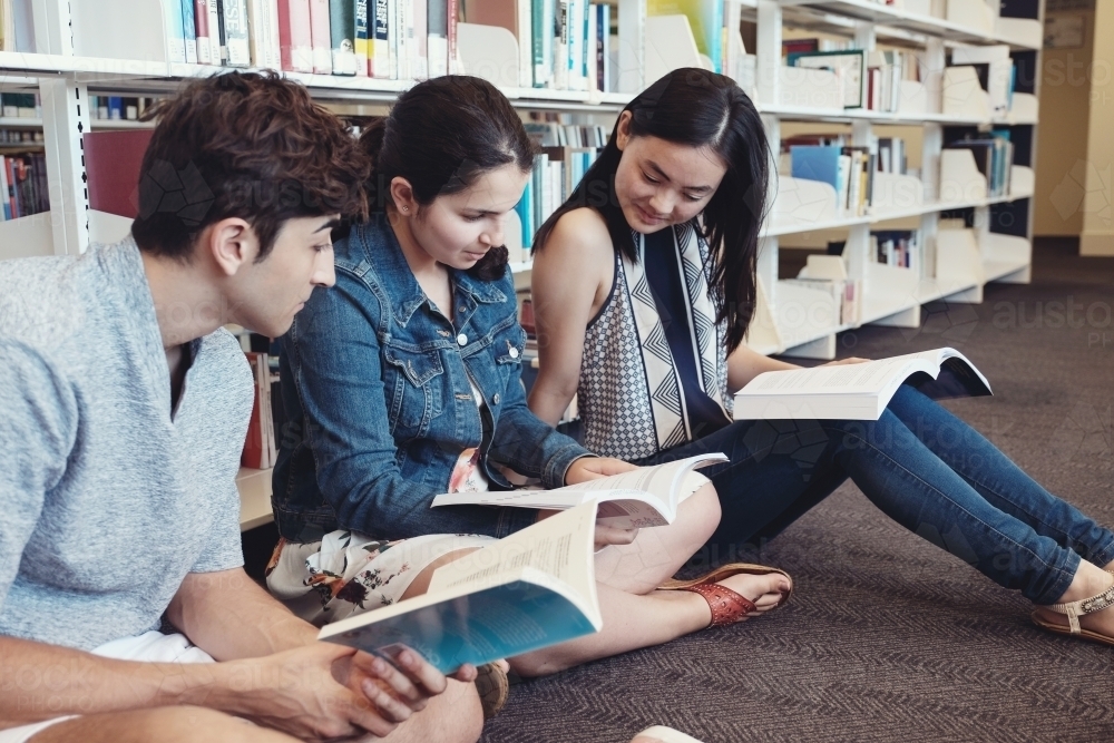 Group of international students reading in university library - Australian Stock Image