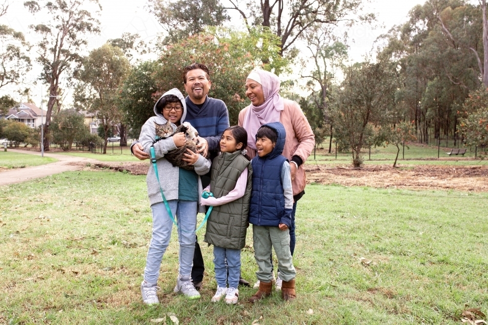 Group of people in a big lawn with one boy holding a cat on a leash - Australian Stock Image