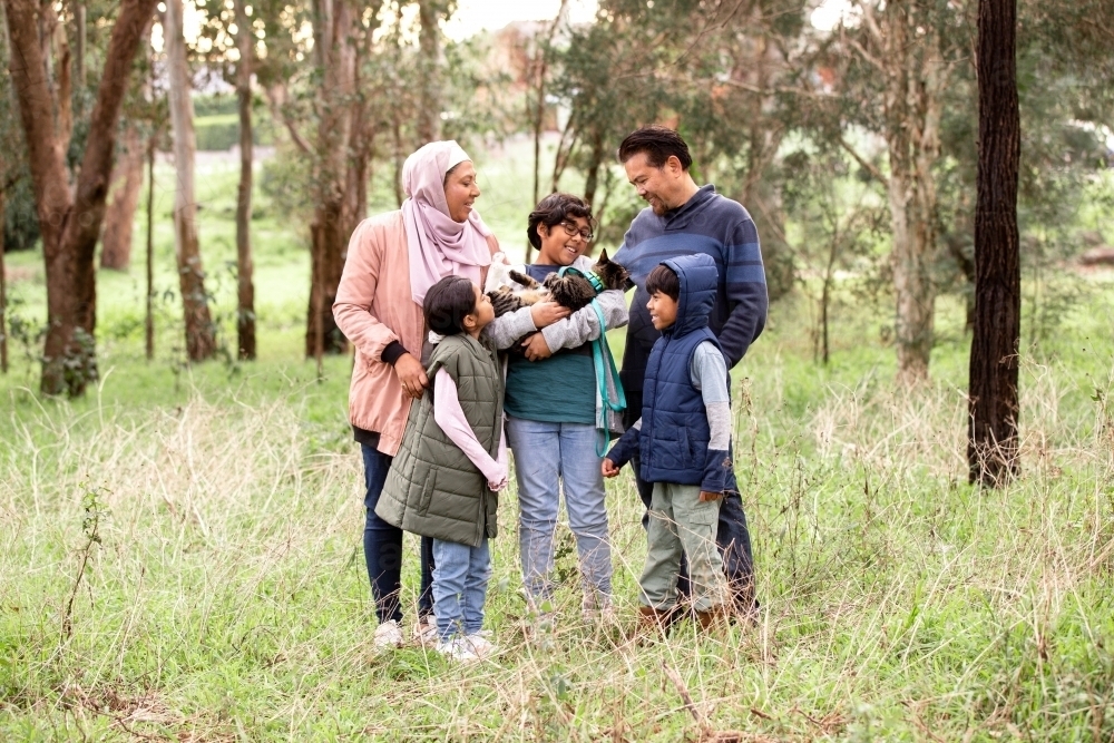 Group of people with one woman wearing pink hijab and a middle aged man three children and a cat - Australian Stock Image