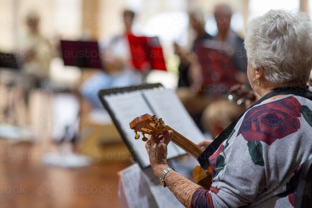 group of senior citizens playing ukulele with one person in focus - Australian Stock Image