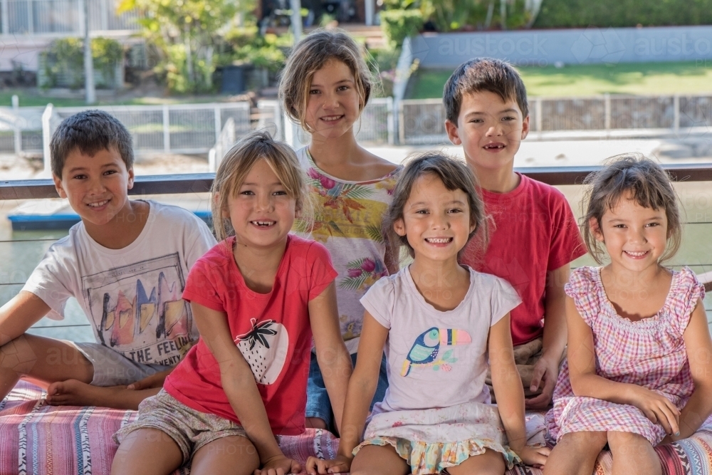 Group of six diverse culture Australian children smiling at camera while close together. - Australian Stock Image