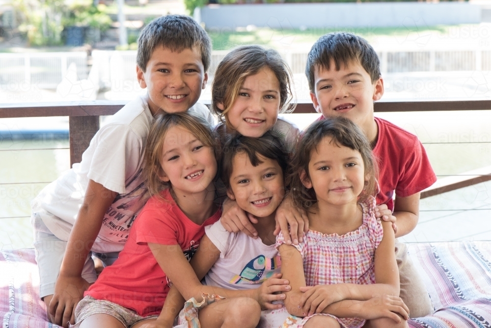 Group of six diverse culture Australian children smiling at camera while close together. - Australian Stock Image