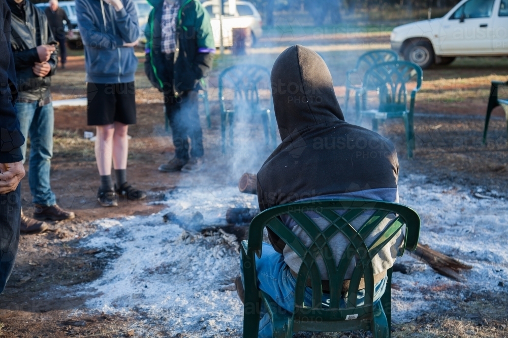 Group of teen boys gathered around a campfire in the morning - Australian Stock Image