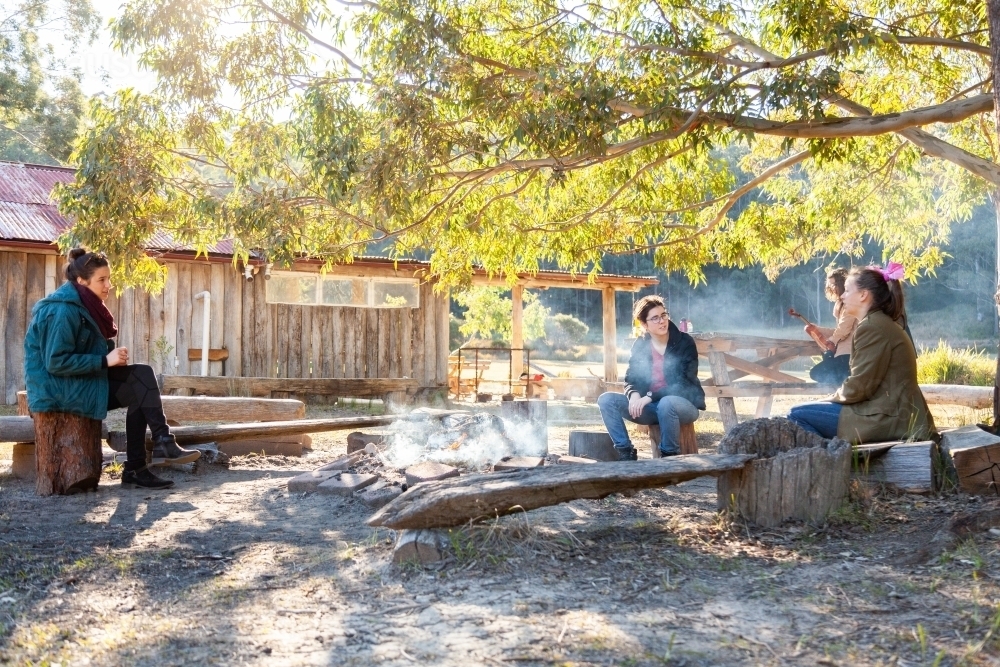Group of teen people sitting around campfire in the morning - Australian Stock Image
