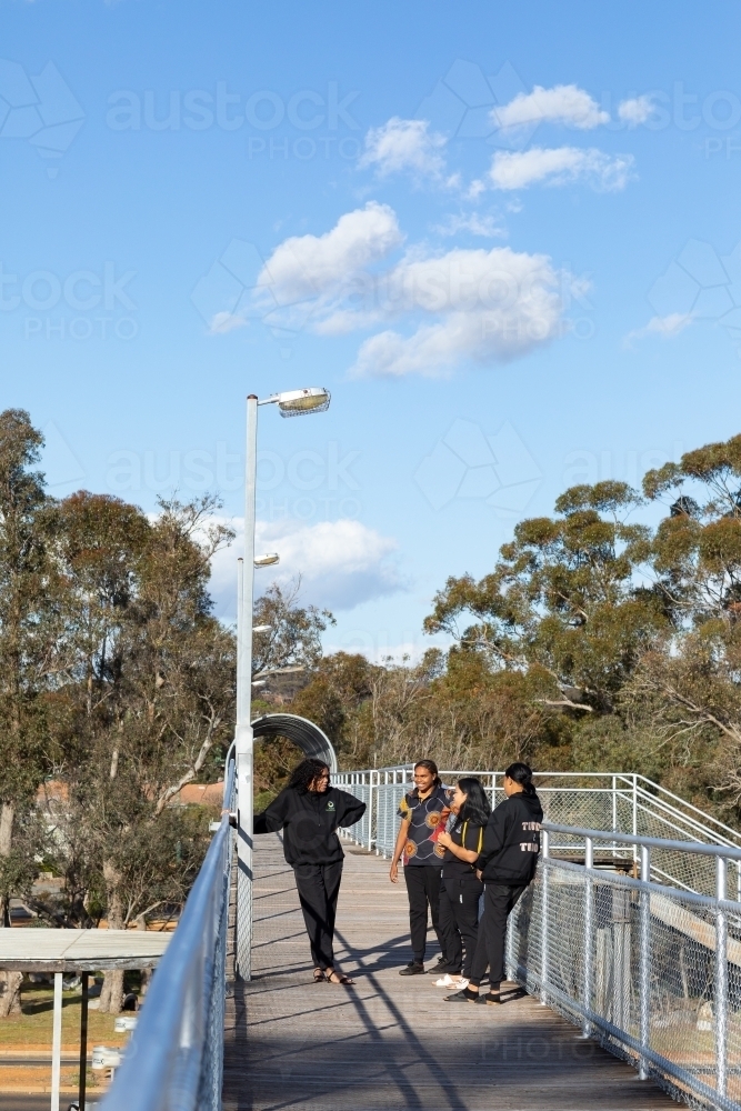 group of teenagers on footbridge on fine sunny day - Australian Stock Image